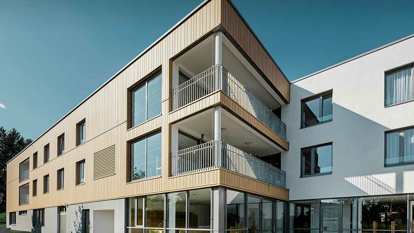 Többlakásos lakóház a fa hatás alternatívájaként – homokszínű Siding elemekkel