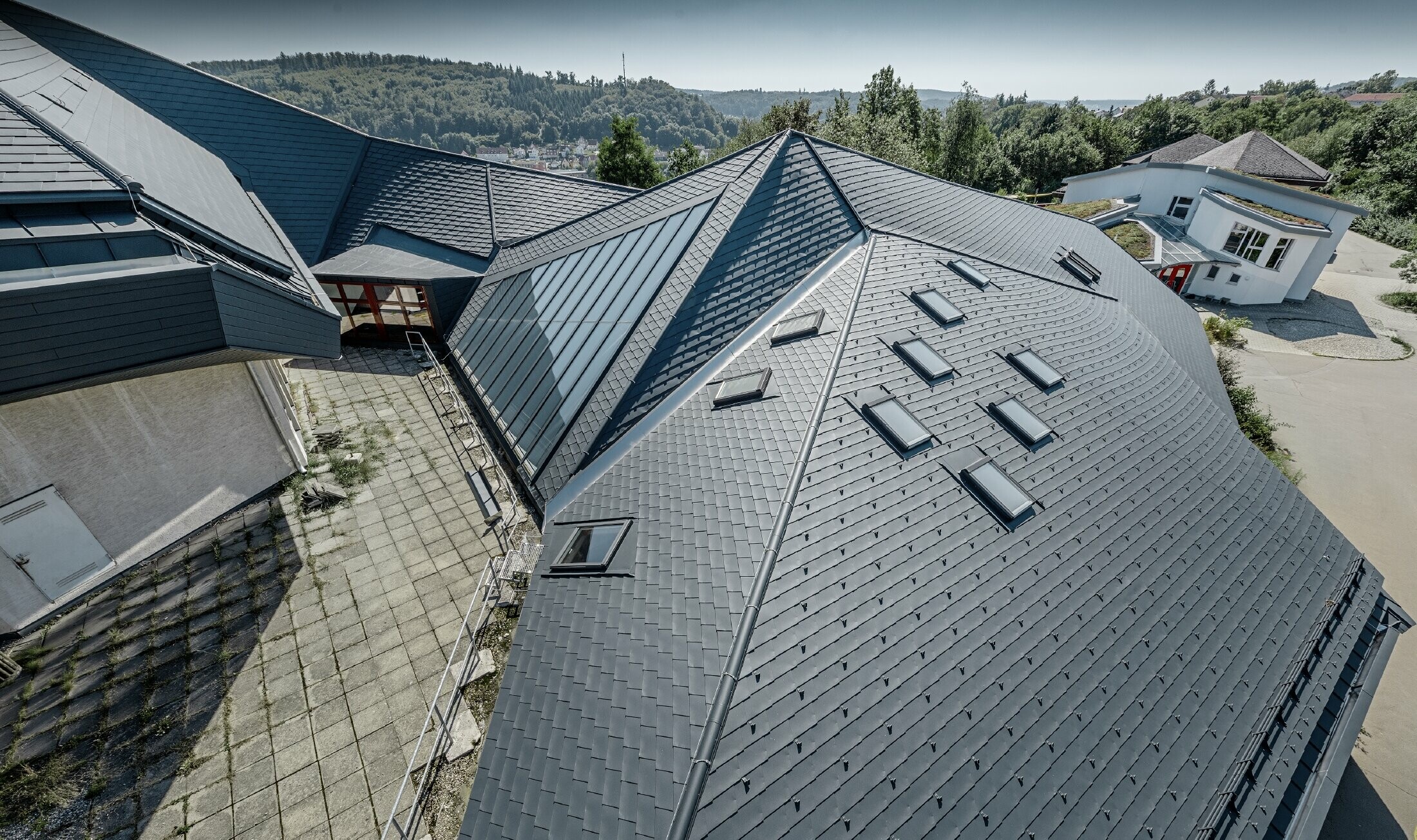 Heidenheimi Waldorf-iskola frissen felújított tetővel, melynek nagy, tagolt felületét antracit színű PREFA tetőfedő zsindellyel burkolták