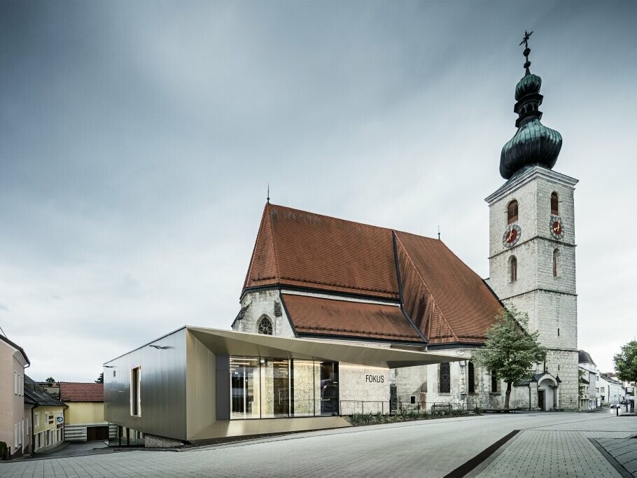 Seitliche Ansicht auf das Pfarrzentrum FOKUS mit PREFA Fassade und die Kirche in Sierning. 