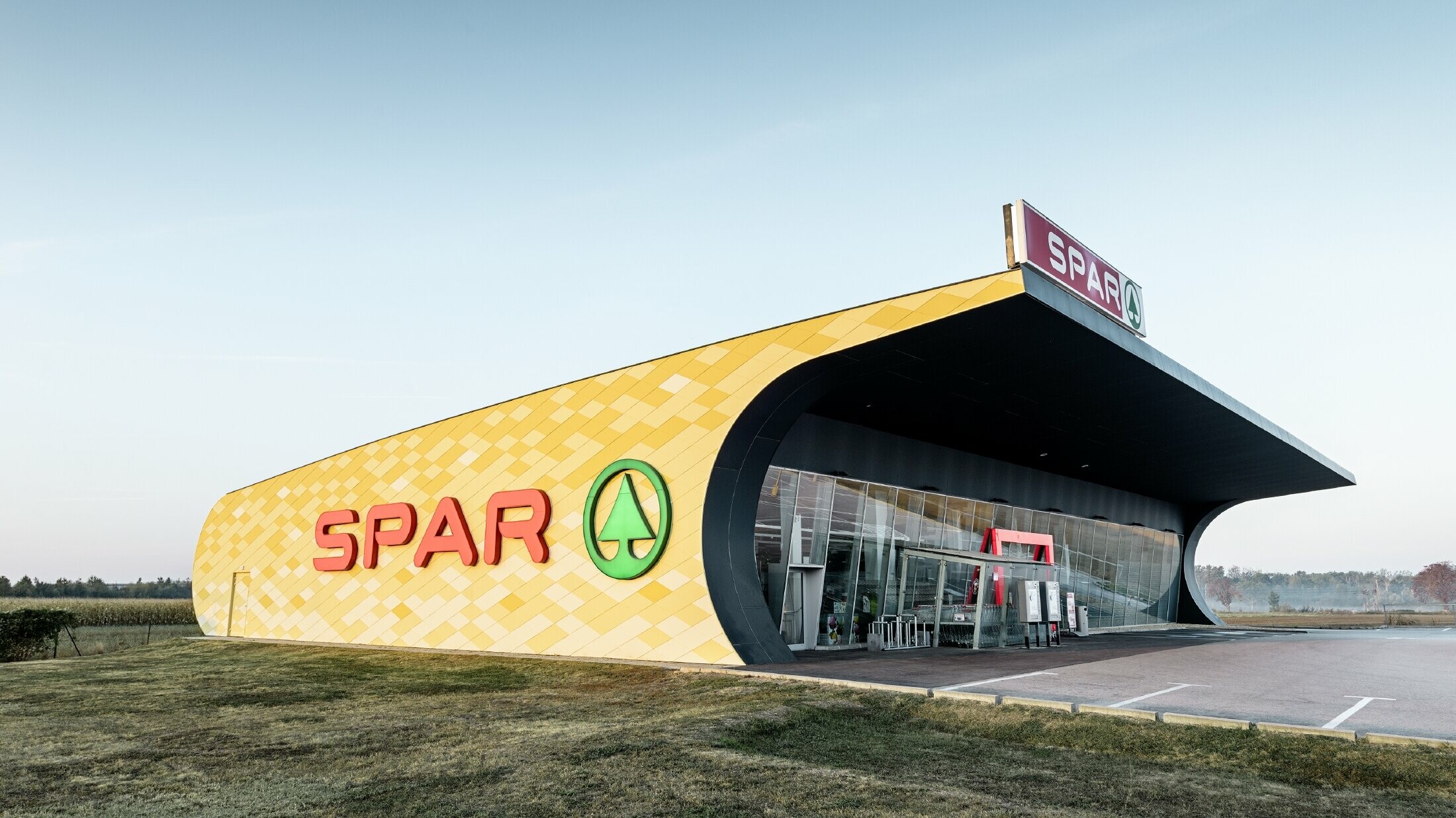 Spar áruház narancssárga alumínium homlokzattal és Spar-logóval