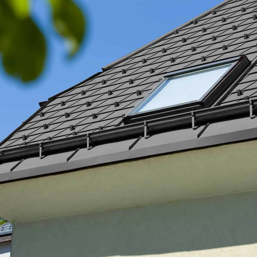 Referenzbild einer PREFA Saumrinne mit Dachfenster mit schwarzem Dach.