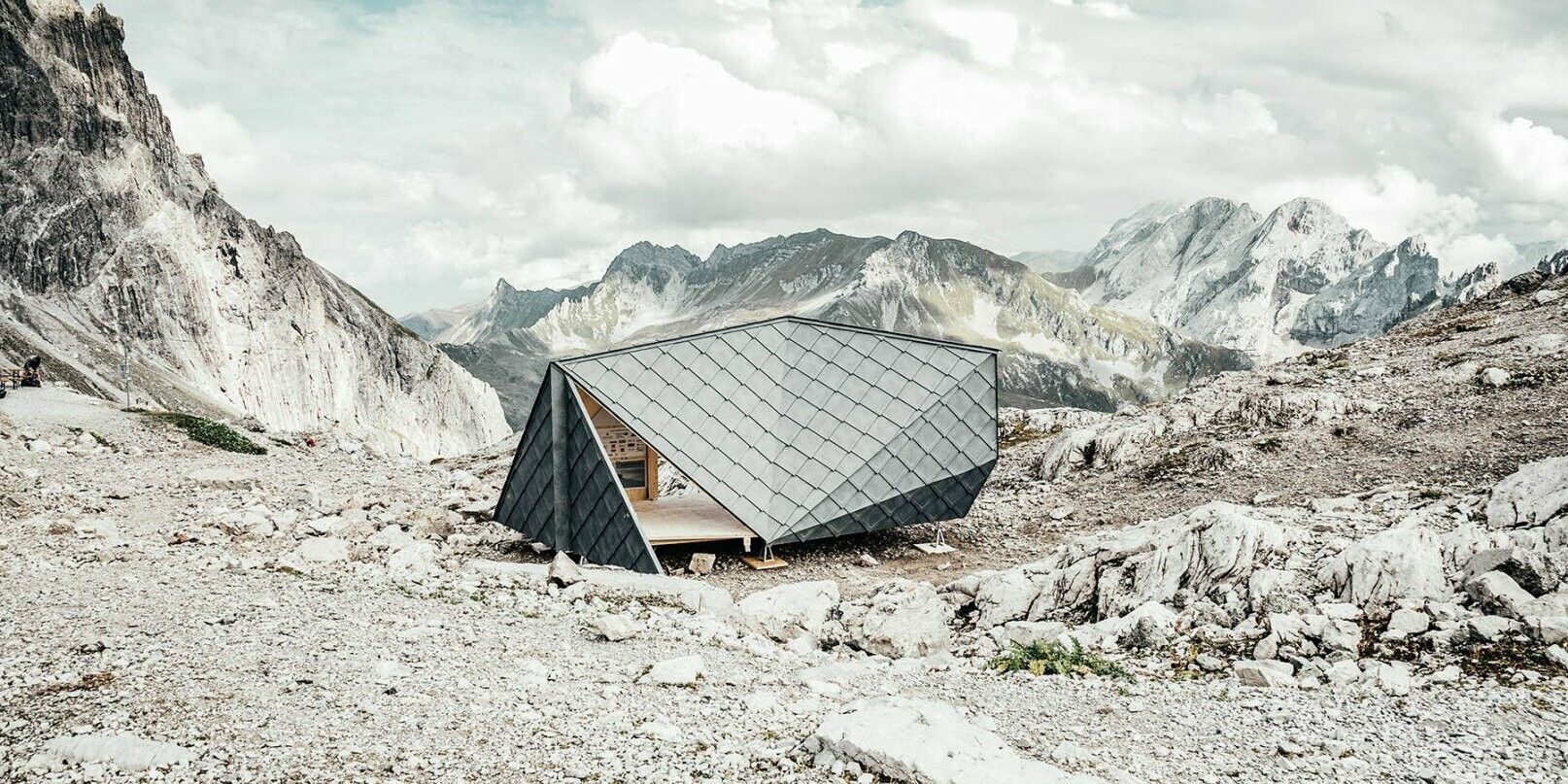 In der Mitte befindet sich die Hütte des Wisswak, die sich harmonisch in das Bergpanorama im Hintergrund einpflegt.