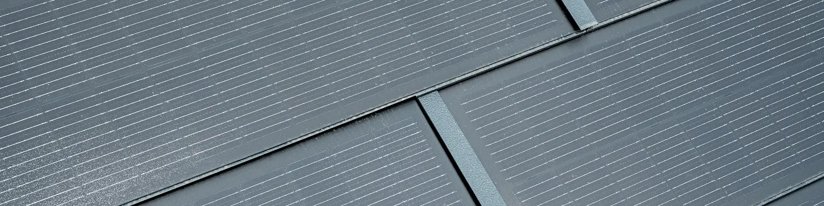 Közeli felvétel beépített kisméretű napelemes tetőfedő panelekről. P.10 antracit színű, kisméretű napelemes tetőfedő panel R.16 Classic elemmel kombinálva. 