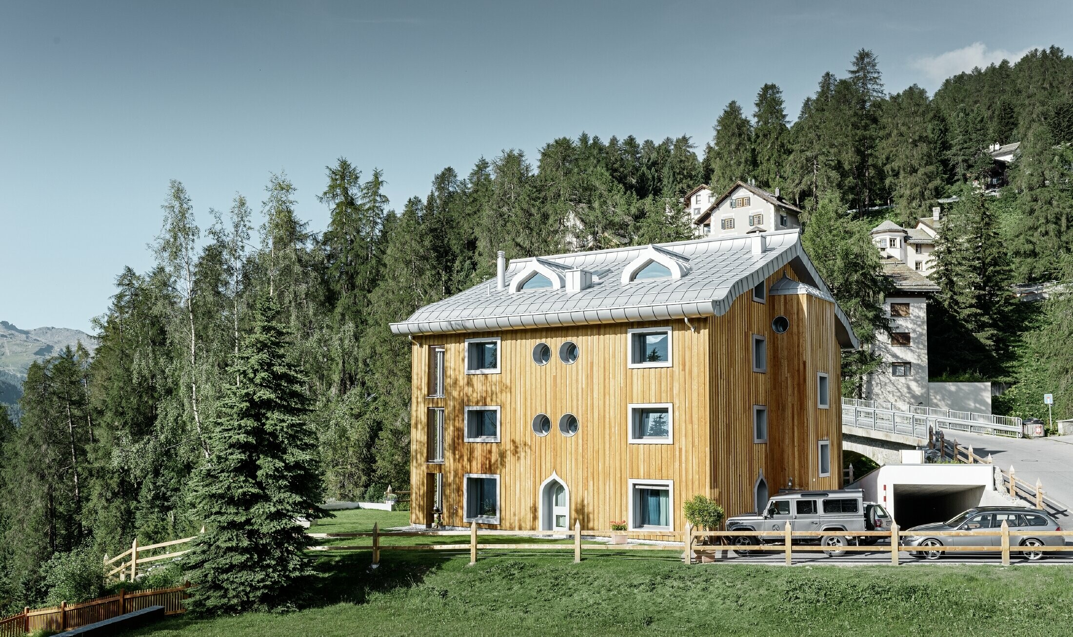 Lakónegyed St. Moritzban fa homlokzattal és alumínium fedéssel, íves eresszel, ezüstmetál színben
