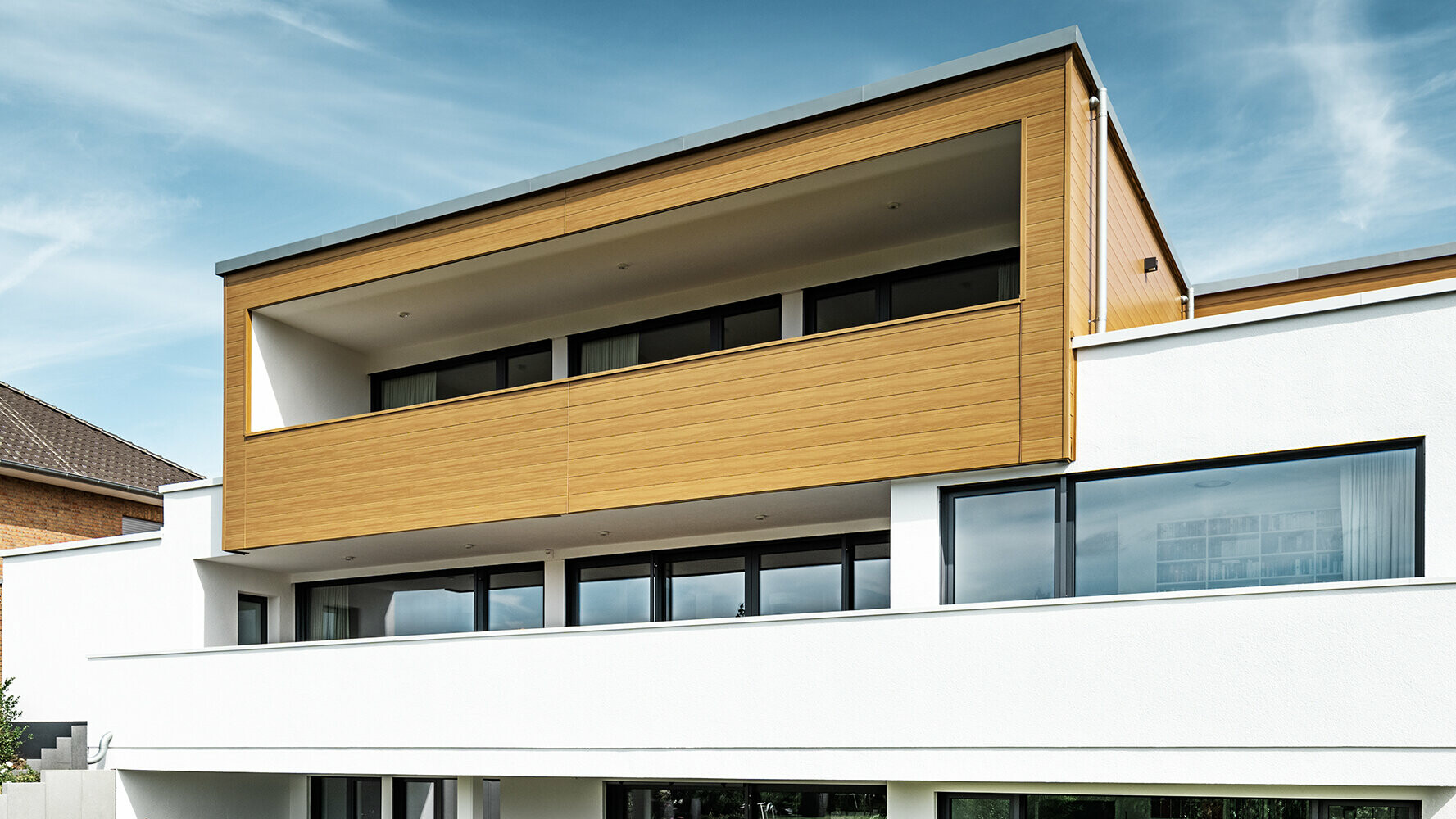 Modern lakóház bézs-szürke színű PREFA Siding elemekkel burkolt erkéllyel.