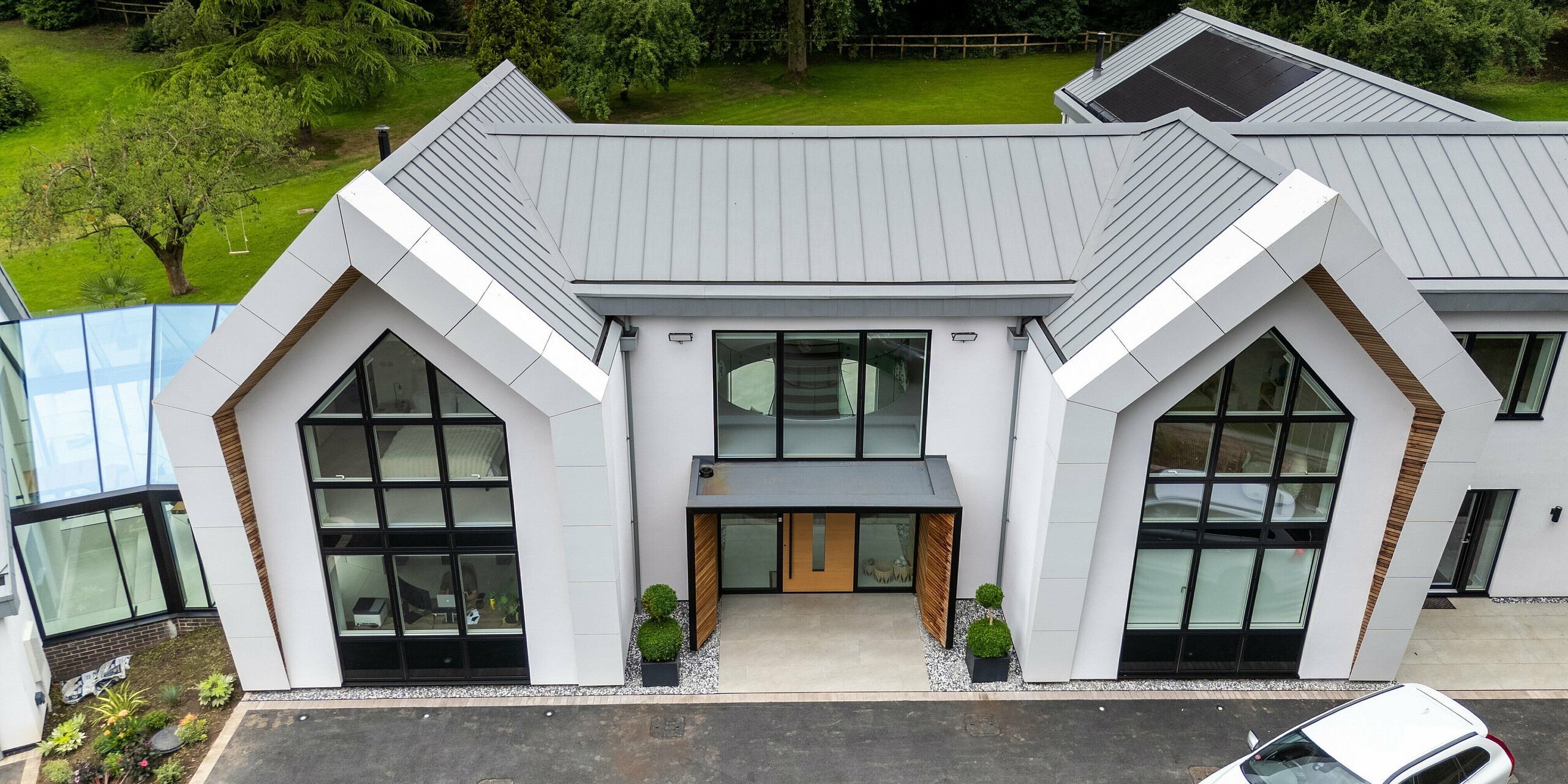 Dieses beeindruckende moderne Zuhause in Draycott In The Clay zeigt das markante PREFALZ Dach in Patinagrau, das perfekt in die natürliche Umgebung integriert ist. Das Dach, mit seiner eleganten Stehfalzdeckung, hebt sich durch seine langlebige und korrosionsbeständige Aluminium-Oberfläche hervor und setzt einen starken Akzent. Große Fensterflächen und die klare Architektur bieten einen atemberaubenden Blick auf die umliegende Natur, während das PREFALZ Dach nicht nur ästhetisch überzeugt, sondern auch höchsten Schutz bietet. Ein perfektes Beispiel für modernes, nachhaltiges Design mit hochwertigen PREFA Produkten.