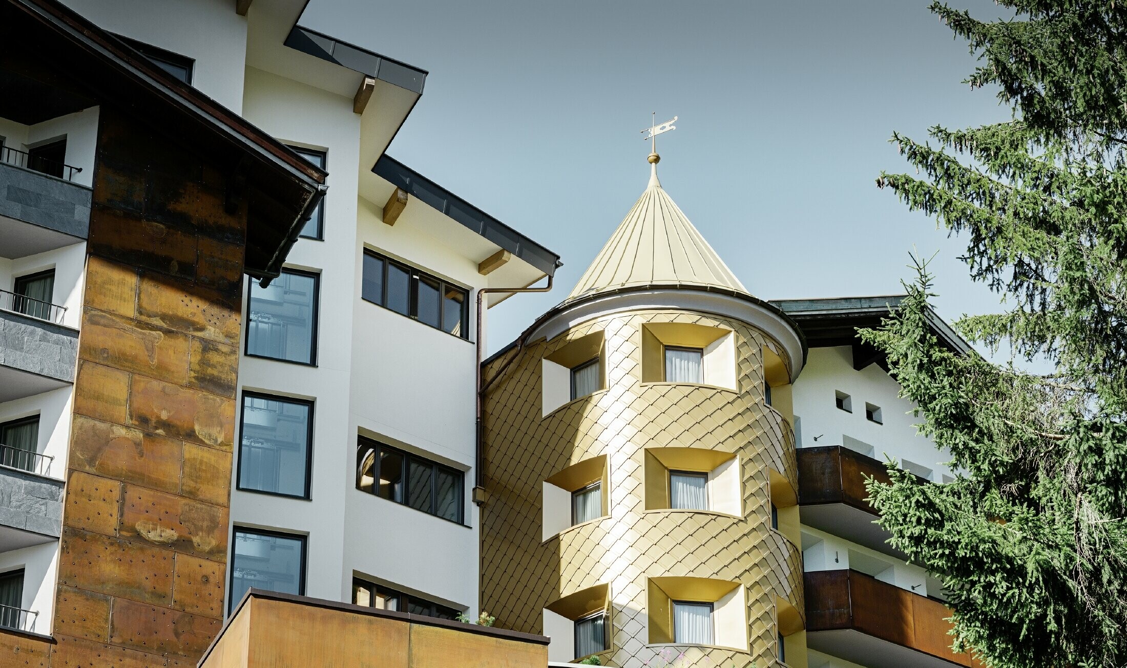 hagyományos megjelenésű szálloda Ischglben, fa erkélyekkel és fa homlokzattal, aranyszínű PREFA alumínium rombusz fedéssel