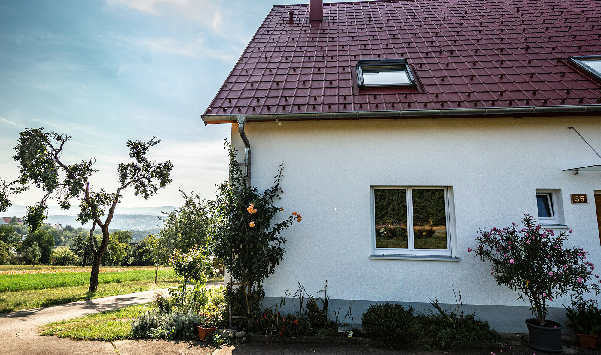 Häuschen am Land, neu saniertes Dach mit PREFA Dachplatte in Oxydrot, Dachfenster und Kamineinfassung.