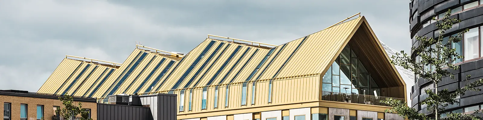 seitliche Frontansicht des Gebäudes in Malmö eingedeckt mit dem Dachsystem PREFALZ in der Sonderfarbe Jaisalmer Gold