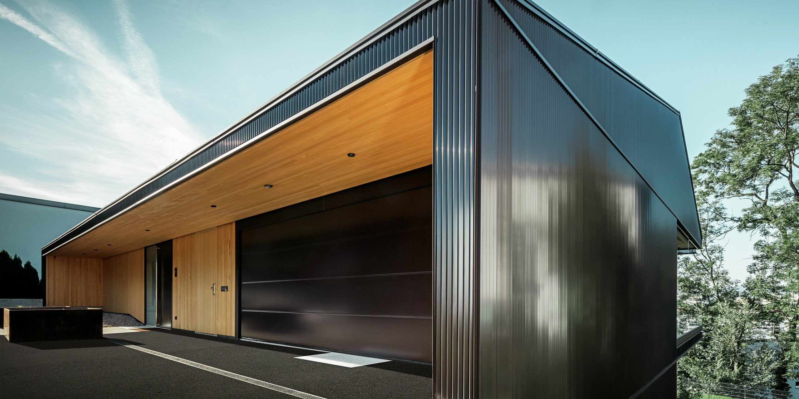 Garageneinfahrt eines Einfamilienhauses in Linz. Die Fassade ist mit dem PREFA Zackenprofil in Nussbraun verkleidet. Das hochwertige Blech bietet zuverlässigen Schutz vor Unwetter.