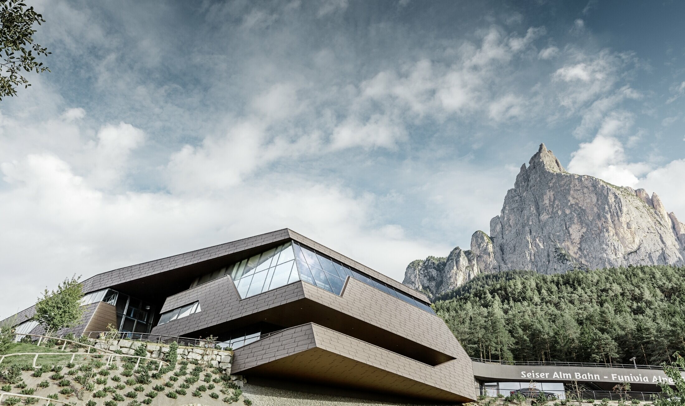 A Seiser Almi sílift újonnan kialakított völgyállomása, a háttérben látható Dolomitokhoz hasonlóan szíbálytalanul elhelyezkedő élekkel és felületekkel, barna színű PREFA alumínium homlokzatburkolattal.