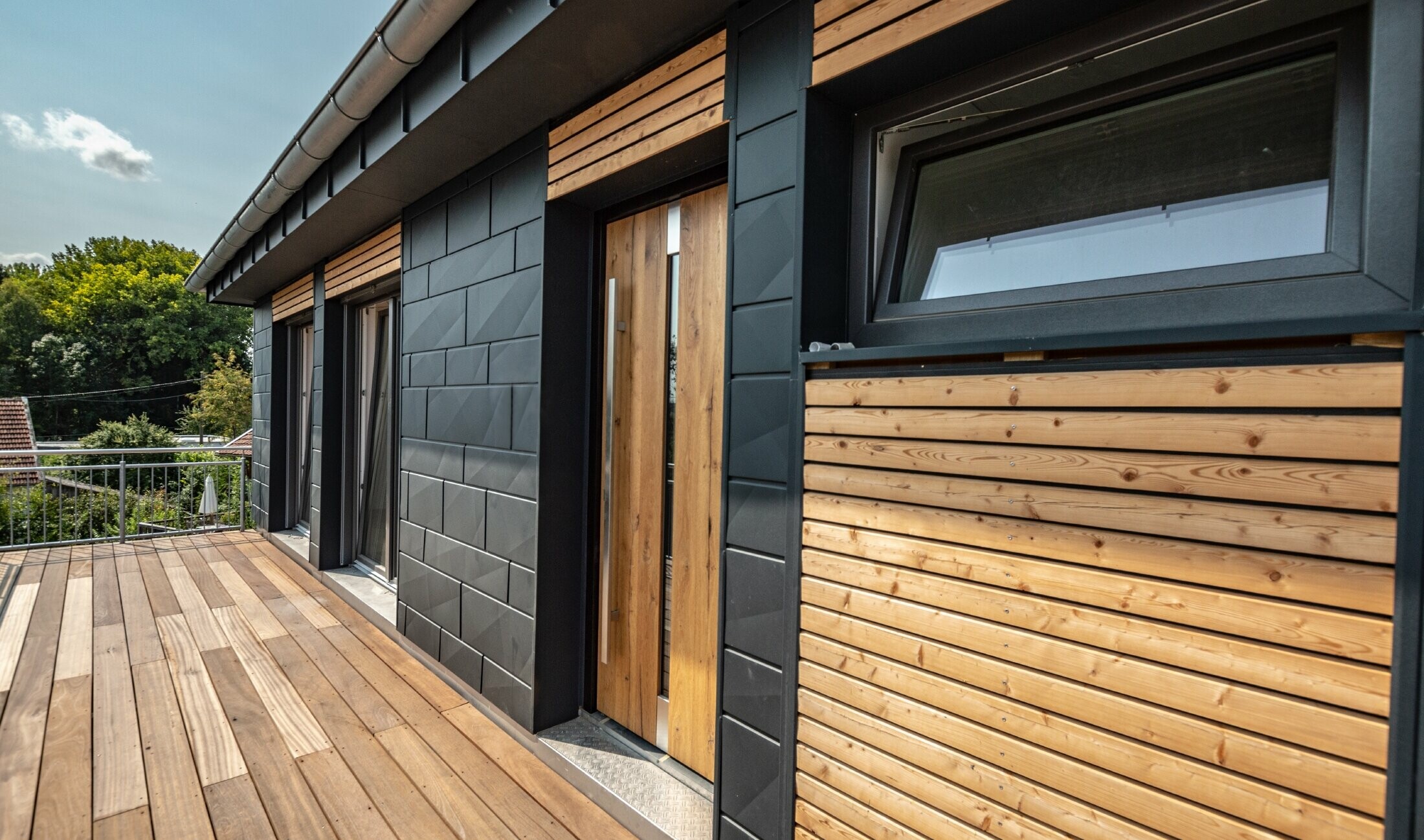Fassadengestaltung durch Mischung der Materialien Aluminium - PREFA Siding.X in Anthrazit - und horizontalen Holzleisten.