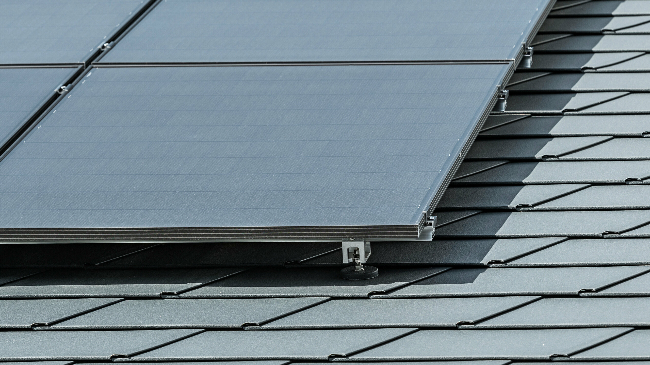 Közelkép a P.10 antracit színű DS.19 PREFA tetőcserépre szerelt fotovoltaikus rendszerről a PREFA Solar Holder Vario segítségével.