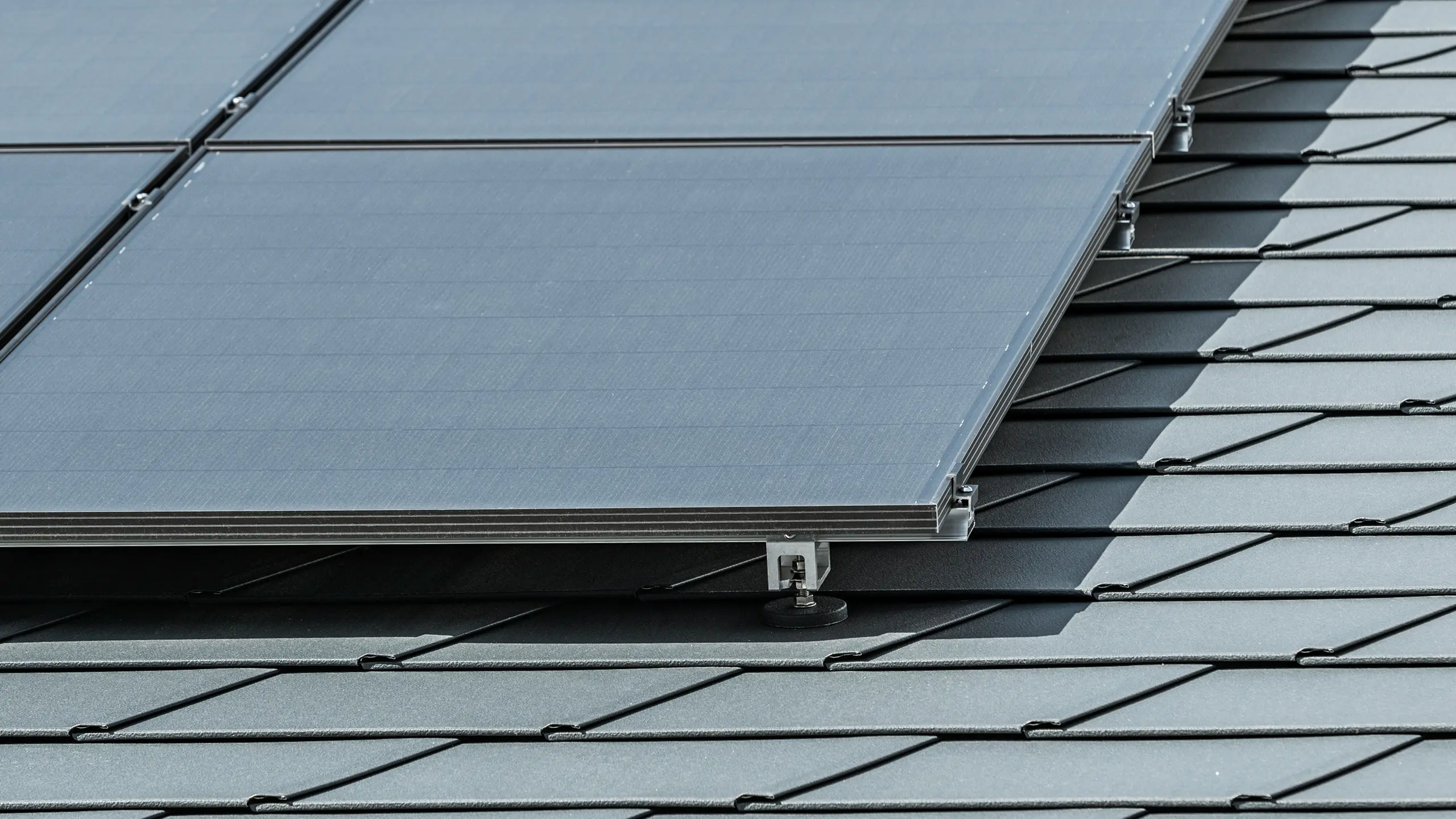 Közelkép a P.10 antracit színű DS.19 PREFA tetőcserépre szerelt fotovoltaikus rendszerről a PREFA Solar Holder Vario segítségével.