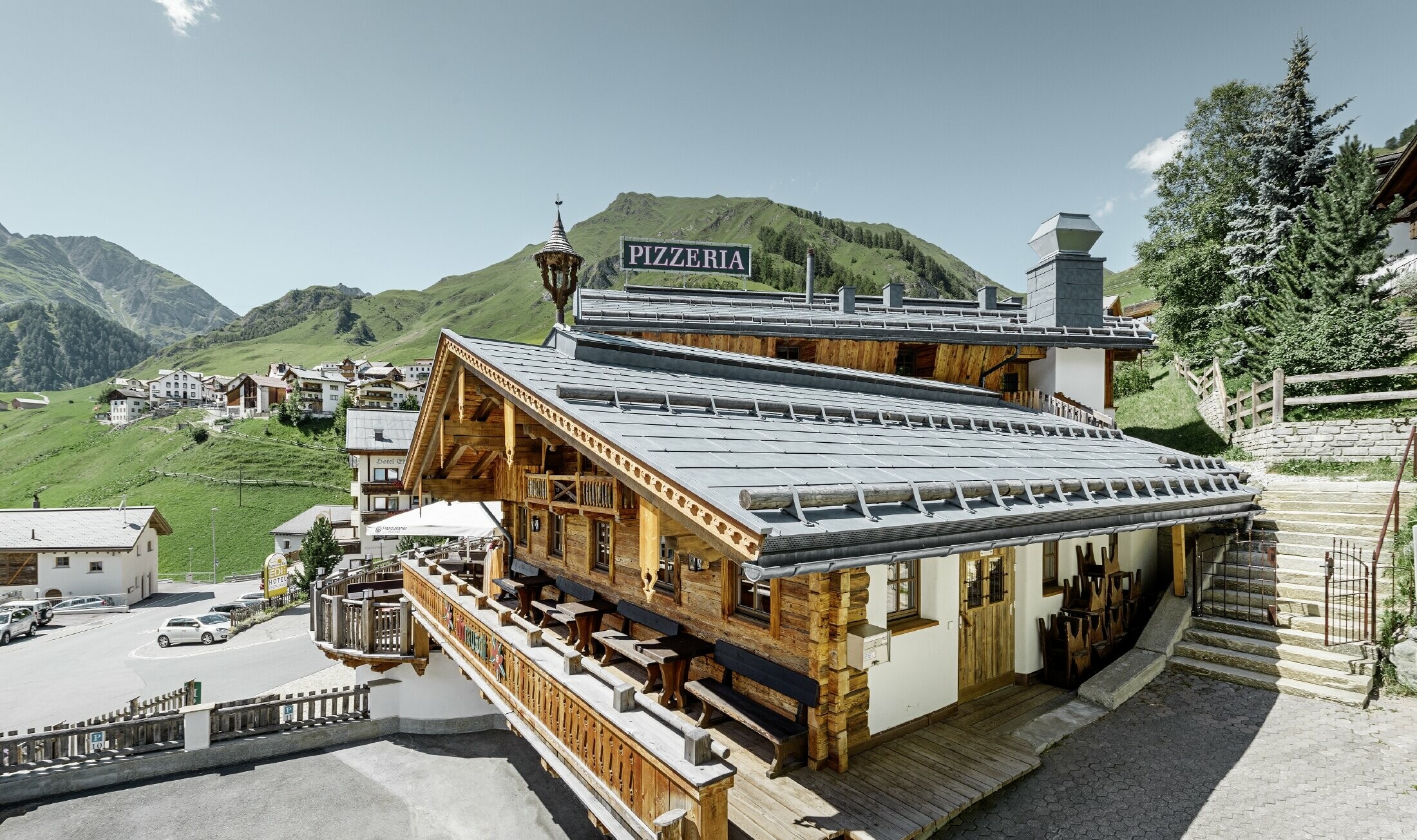Almrausch étterem Bergennel a háttérben és márványszürke színű PREFA FX.12 tetőfedő panel fedéssel, hófogórönk tartókkal