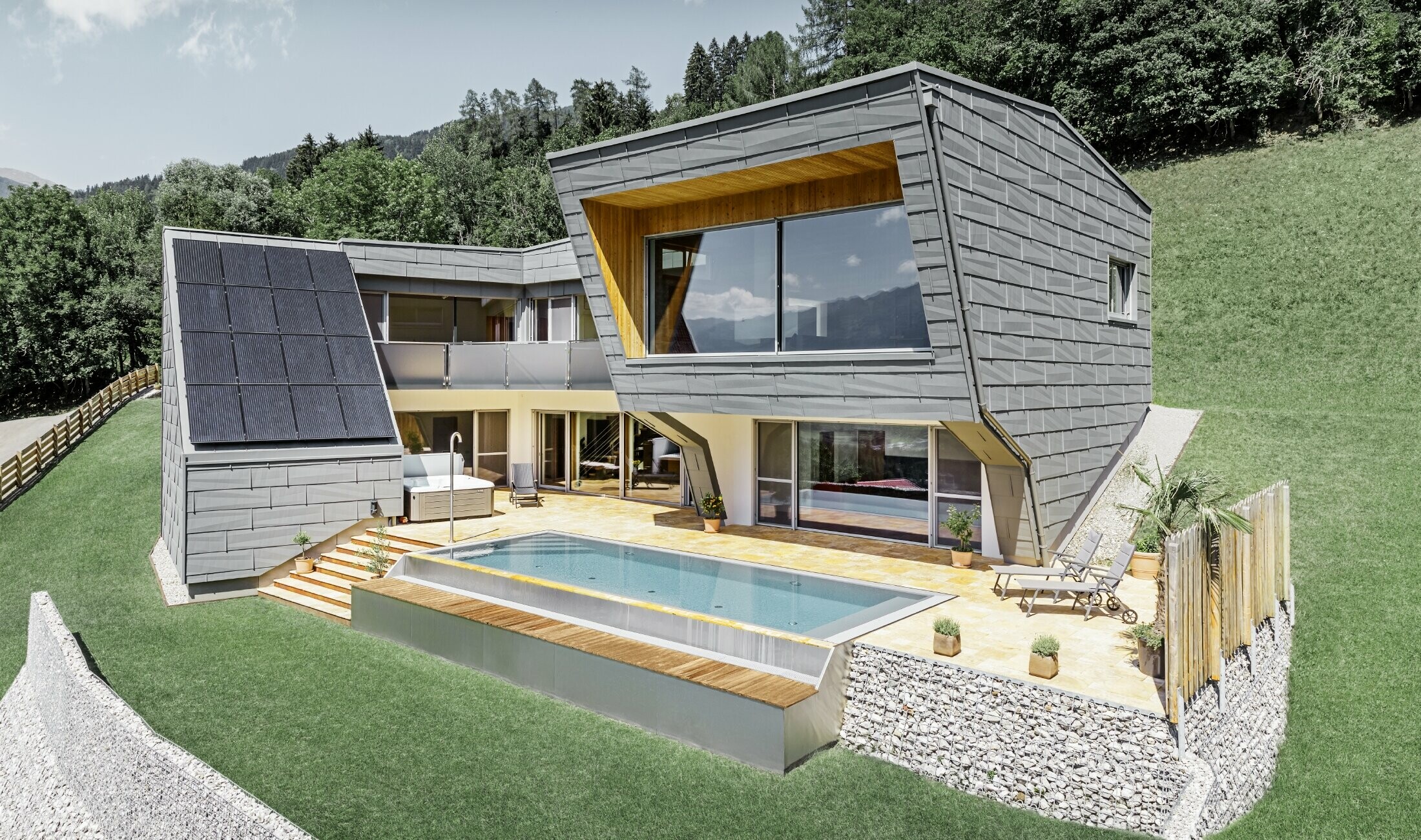 Modernes Einfamilienhaus in Hanglage mit Swimmingpool wurde mit dem Fassadenpaneel FX.12 von PREFA in P.10 Hellgrau verkleidet.