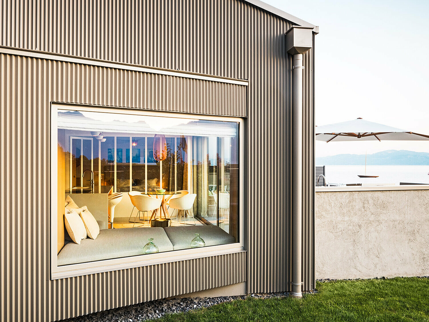 Az épület oldalnézete fogazott alumíniumhomlokzattal, a megvilágított belső tér egy része is látható.