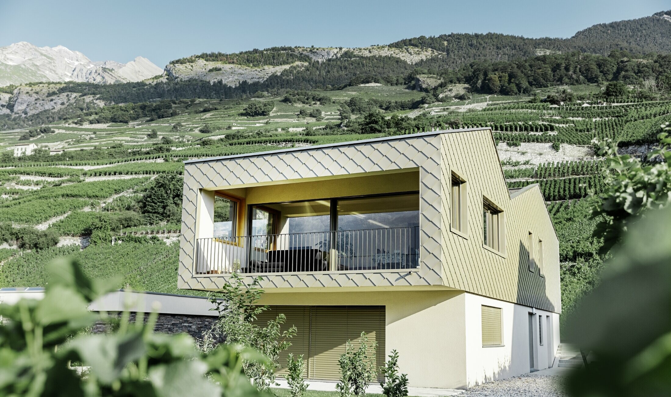 Modern családi ház Rhônetal szőlőhegyeinek közepén, 4 különböző tetősíkkal, nyitott galériával és bronz színű rombusz homlokzattal