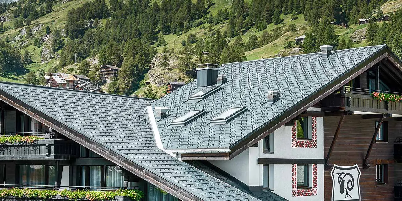 Hotel Alpenhof Zermatt, háttérben a Matterhornnal, erkélyekkel, sötét fa homlokzattal és antracit színű PREFA alumínium fedéssel
