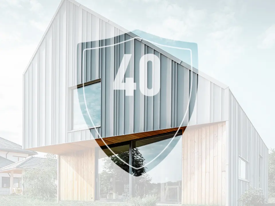 A képen a PREFA alumínium termékekre vonatkozó garanciát jelképező „40” számmal ellátott tábla látható egy modern családi ház előtt.