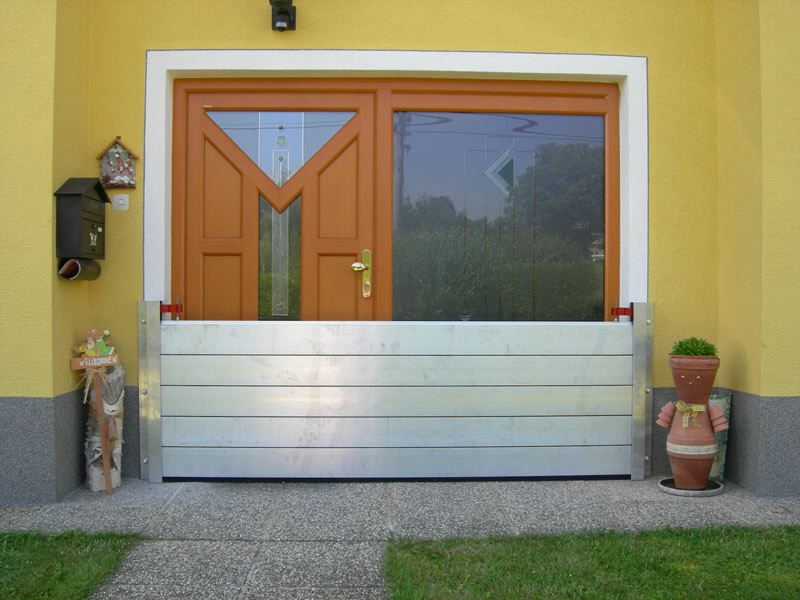 Családi ház bejárati ajtaja a modern PREFA árvízvédelmi rendszerrel