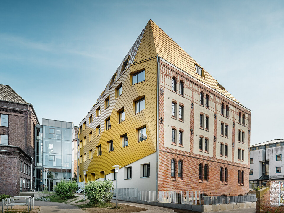 Das Studentenwohnheim aus der Froschperspektive: Die historische Fassade erstreckt sich rechts, die neue PREFA Hülle stülpt sich links bis über das Dachgeschoss.