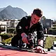Zu sehen ist der PREFA Mitarbeiter Felix Gruber auf dem Dach eines Einfamilienhauses in Zirl, der gerade ein PREFA Dachprodukt montiert.