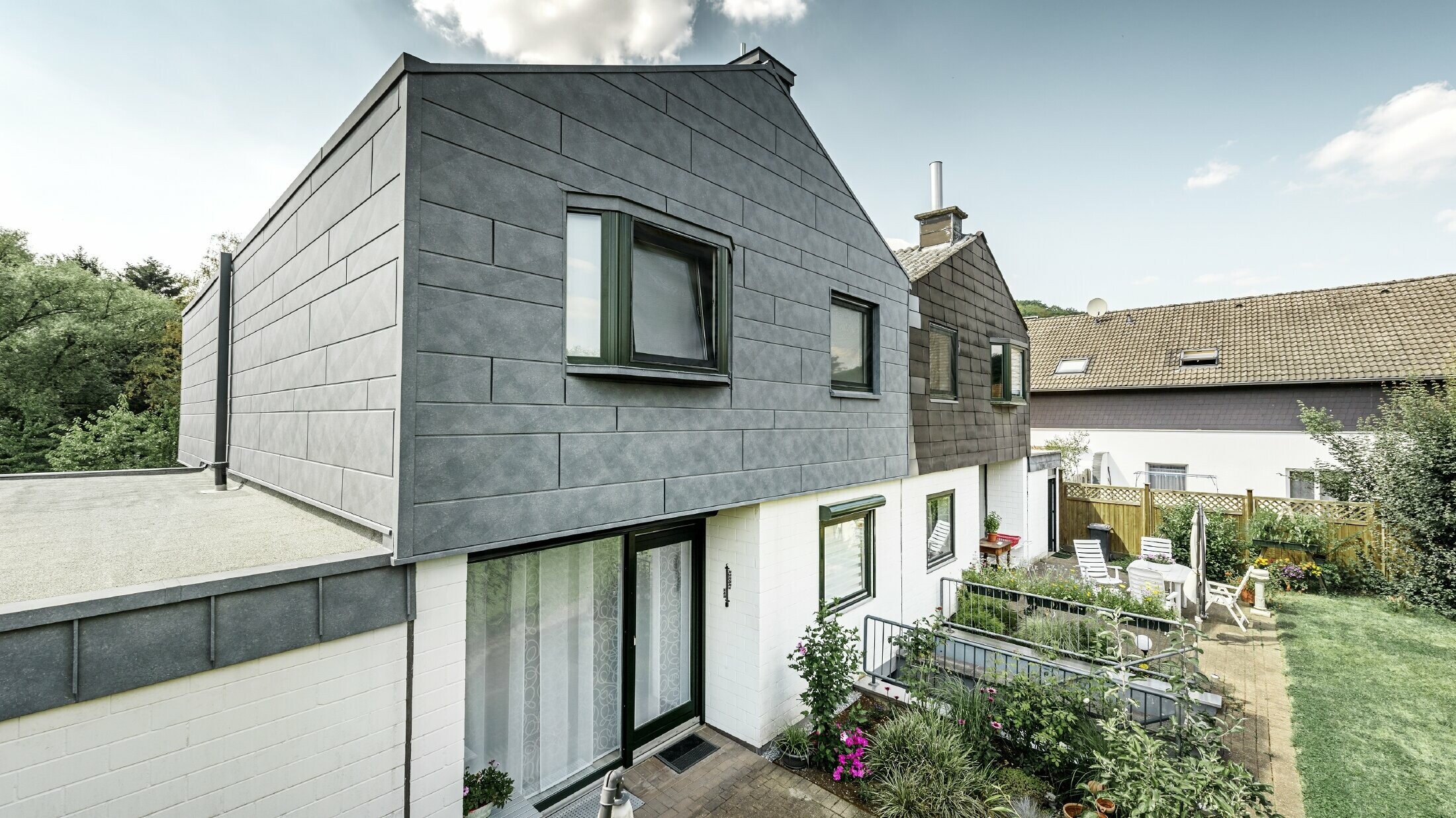 A ikerház felső részét PREFA Siding.X homlokzati elemekkel, P.10 márványszürke színben újították fel. Mellette, összehasonlításképpen, a felújítás előtti állapotban látható a ház másik fele.