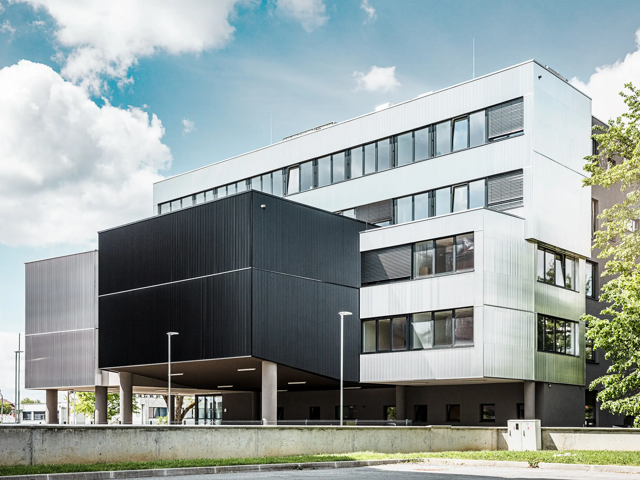 A bjevolari zeneiskola oldalnézete modern PREFA homlokzattal, fogazott profillal. A homlokzat fekete és natúr alumínium színben készült, a geometrikus formák pedig markáns, minimalista dizájnt alakítanak ki.