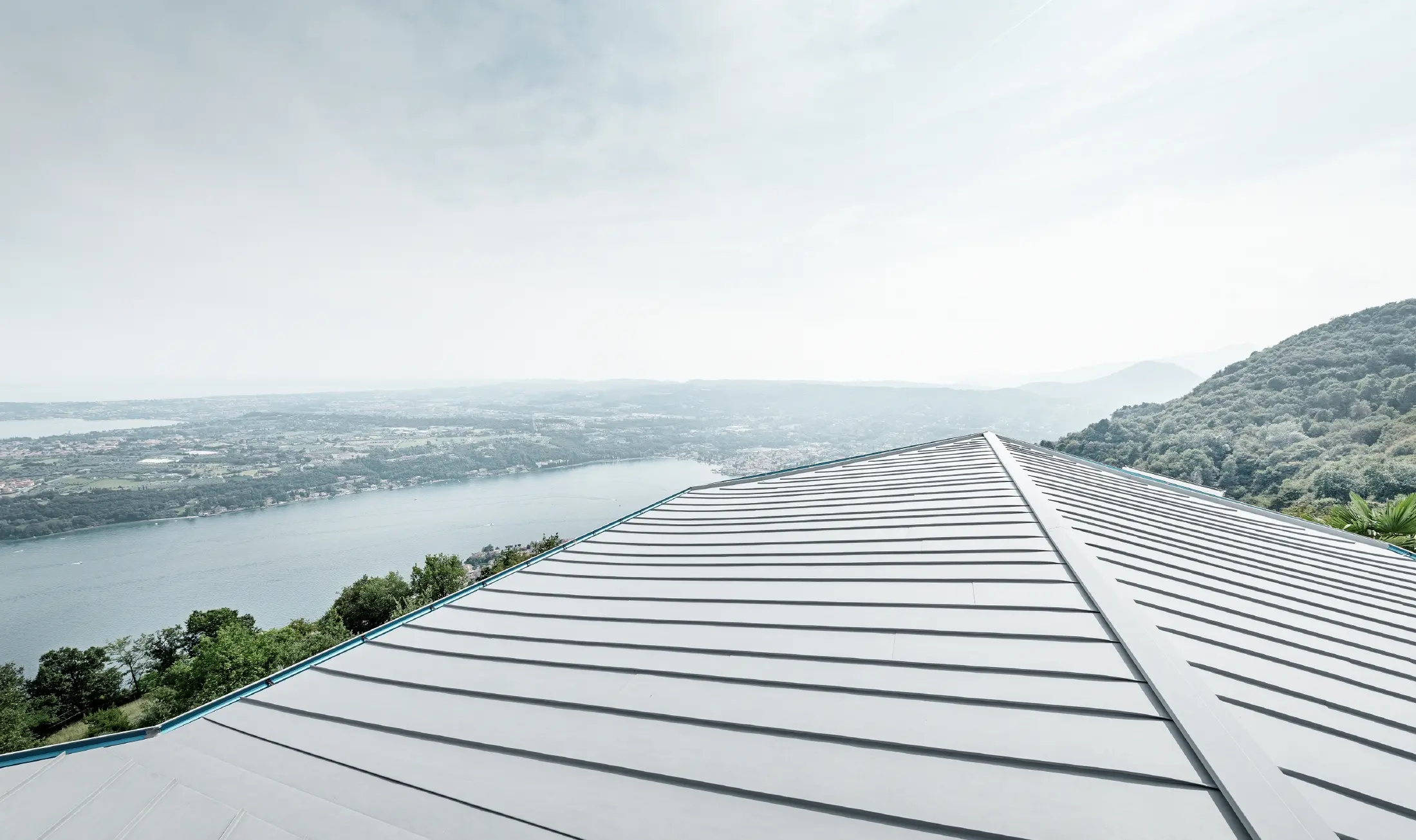 Magaslaton fekvő ház, panorámával a tájra, nagy terasszal és úszómedencével, és patinaszürke állókorcos fedéssel