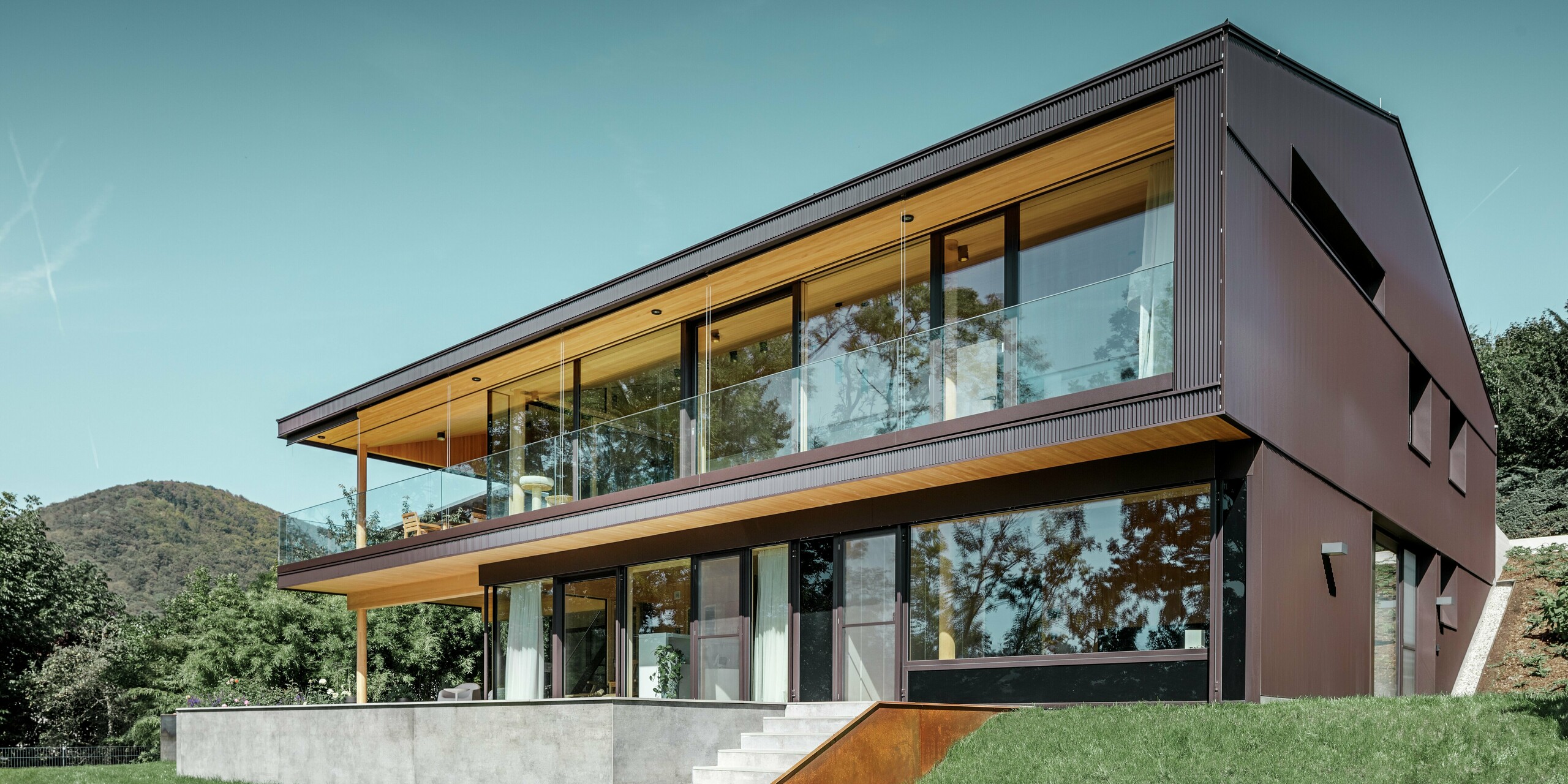 Dieses moderne Einfamilienhaus in Linz verfügt über eine großzügige Terrasse und große Fenster auf der Gartenseite. Die Fassade wurde mit PREFA Zackenprofil in Nussbraun verkleidet. Die einzigartige Fassade aus stranggepresstem Aluminium verändert ihr Erscheinungsbild je nach Lichteinfall und verleiht dem Objekt einen einzigartigen Look.