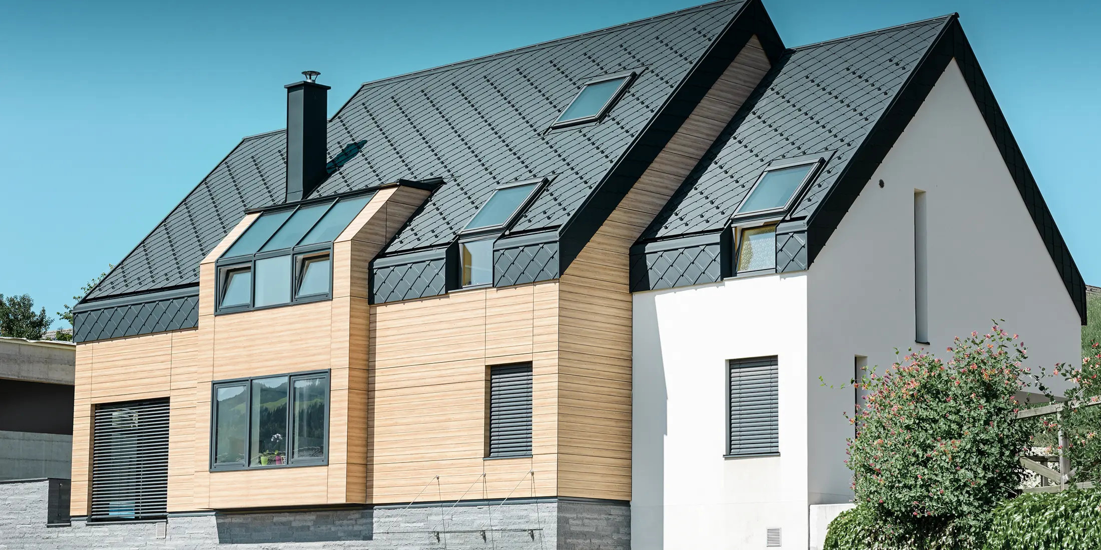 Korszerű új épület, ahol a tetőhéjazat a homlokzat felső része fölé is kinyúlik, tetőhéjazatként az antracitszínű alumínium tetőfedő rombuszt használták