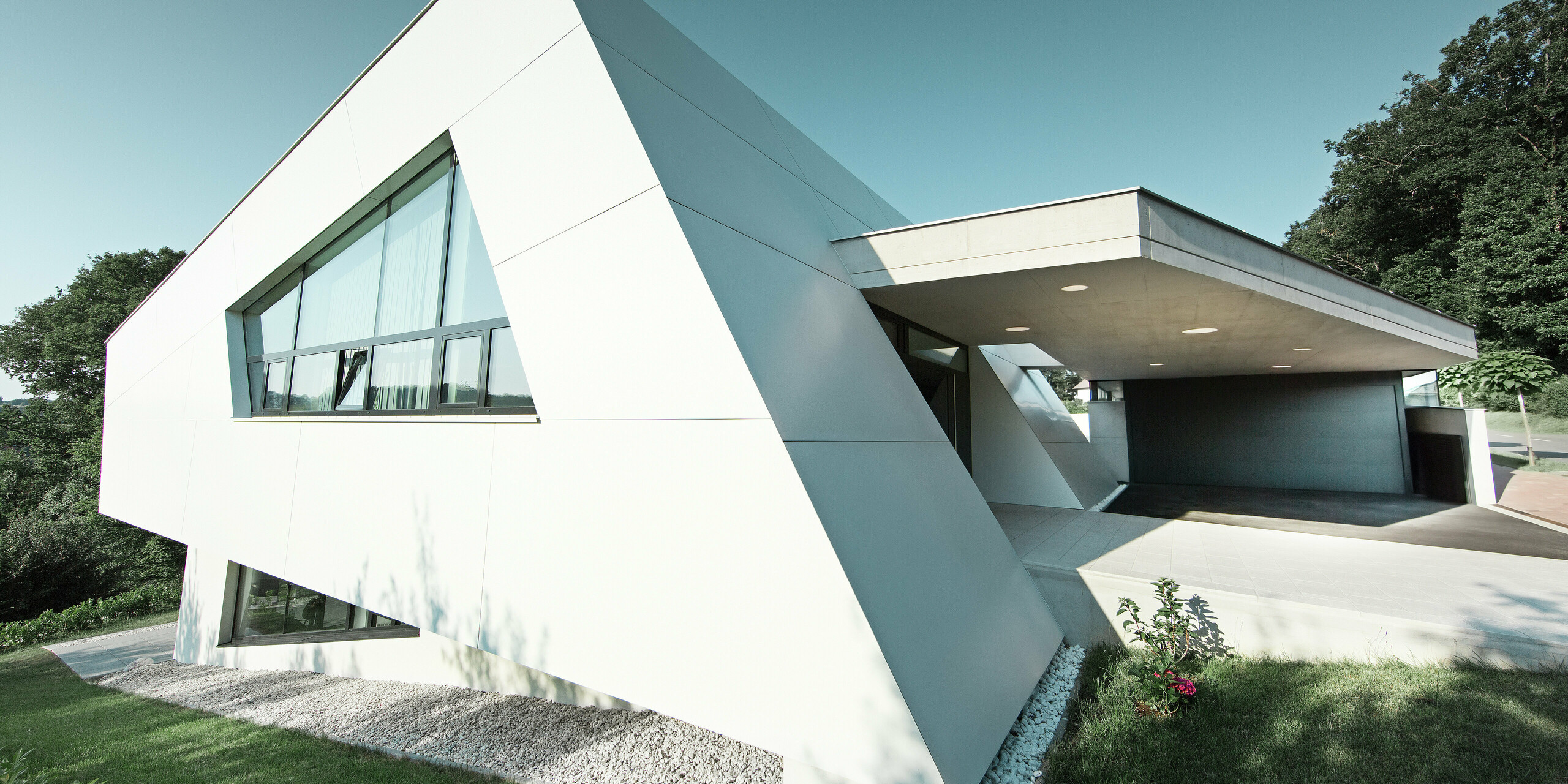 Die präzise ausgeführte Front dieses Einfamilienhauses zeigt die skulpturale Wirkung der PREFA Aluminiumfassade. Die großformatigen Aluminium Verbundplatten in Reinweiß verschmelzen mit den Fensterflächen zu einer außergewöhnlich dynamischen Architektur.