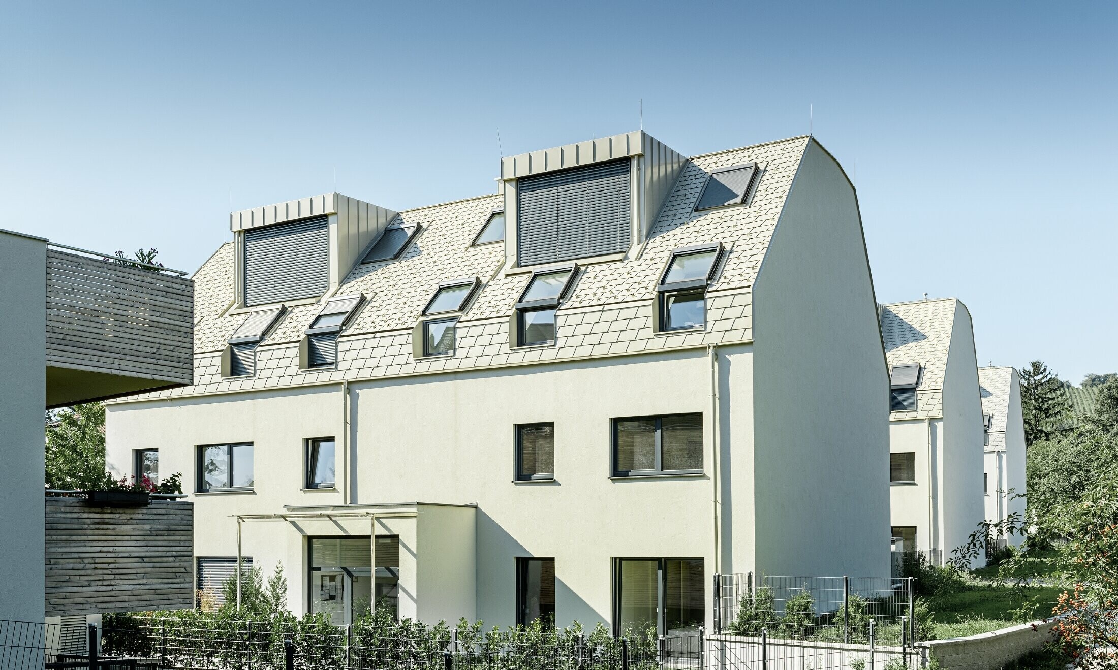 új építésű lakónegyed nagy alumínium burkolatú tetőfelülettel és sok tetősíkablakkal