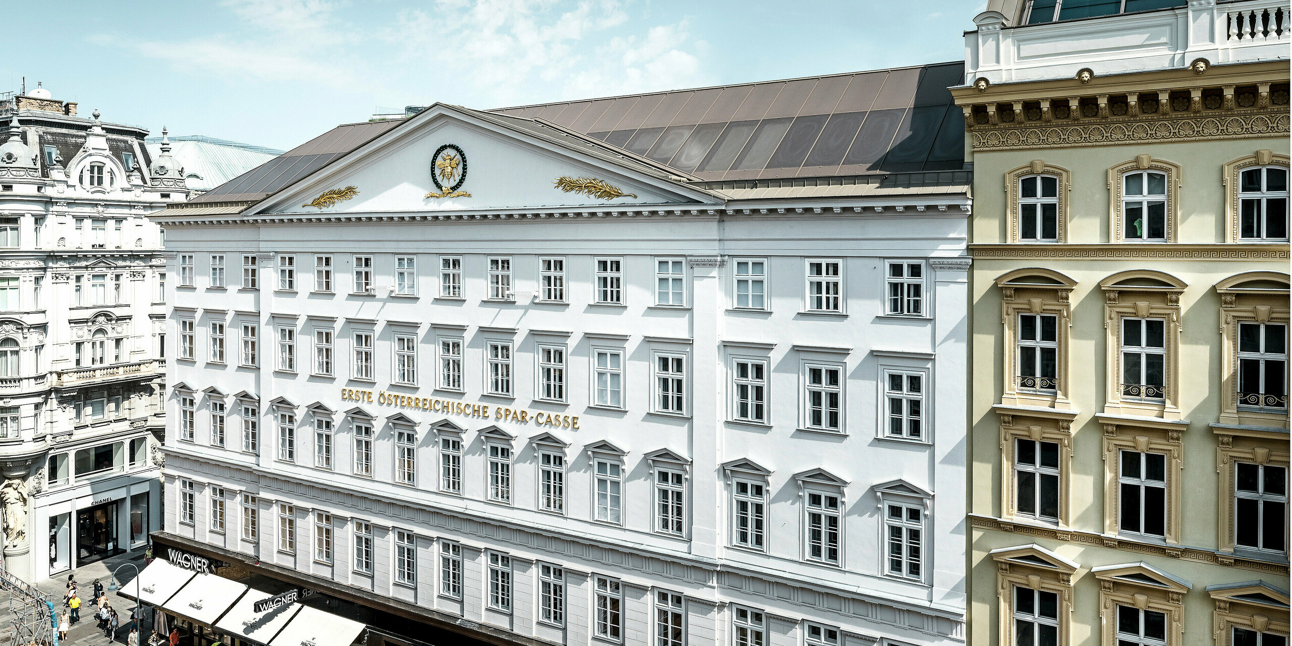 Seitliche Frontansicht des Hotels mit der historischen Fassade und dem bronzenen Aluminiumdach.