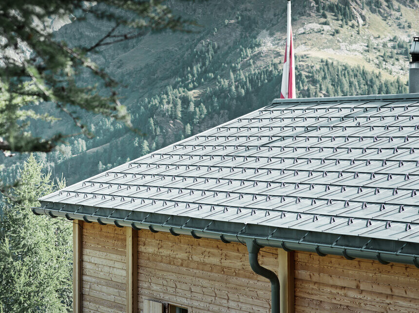 A svájci kunyhót a PREFA Classic elem és a PREFA függő ereszcsatorna borítja, amely a biztosító tartóelemhez van rögzítve.