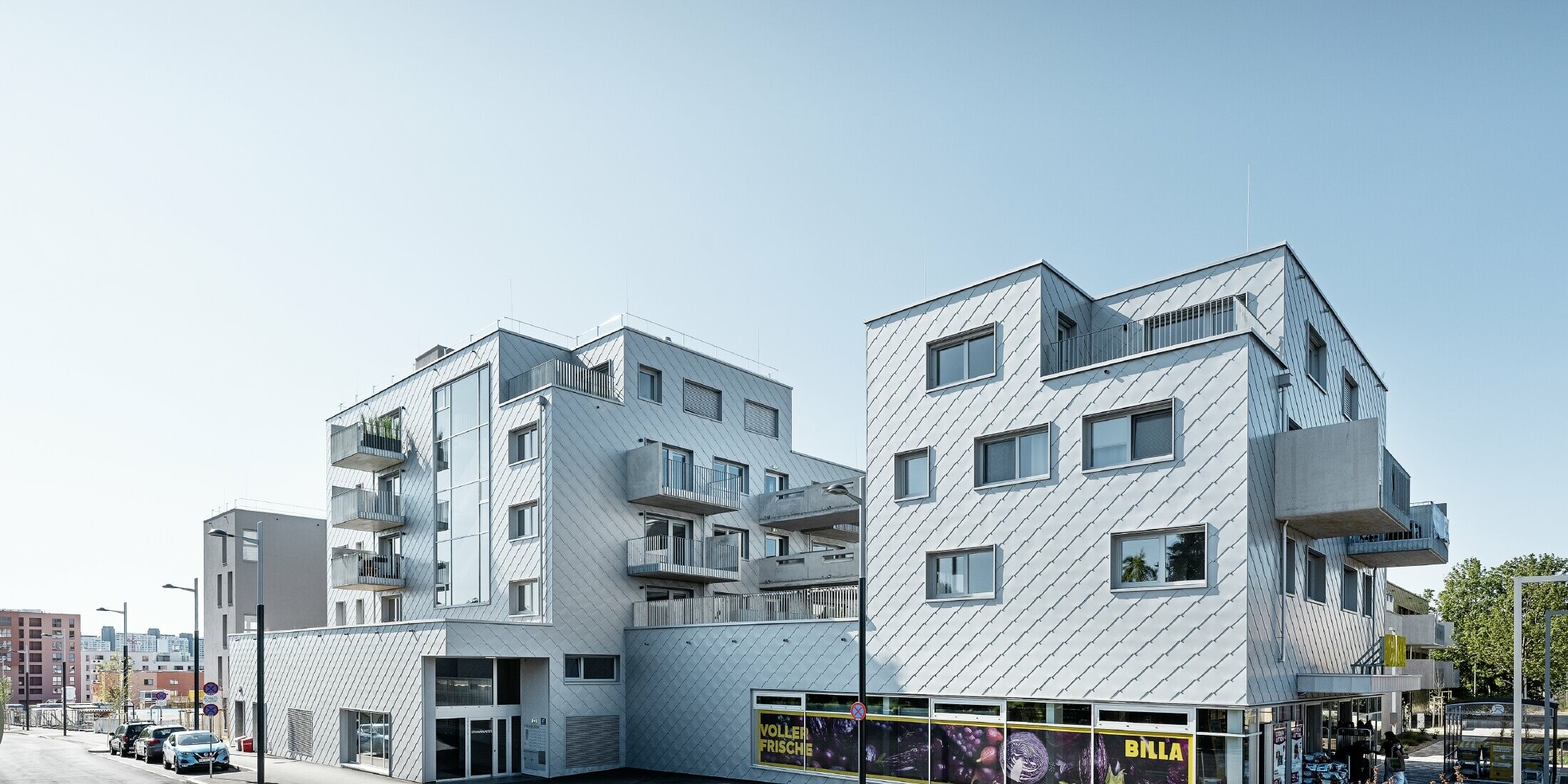 Lakókomplexumok lapos tetővel és rombusz burkolattal a homlokzaton a 44 x 44-es PREFA homlokzatburkoló rombusszal ezüstmetál színben
