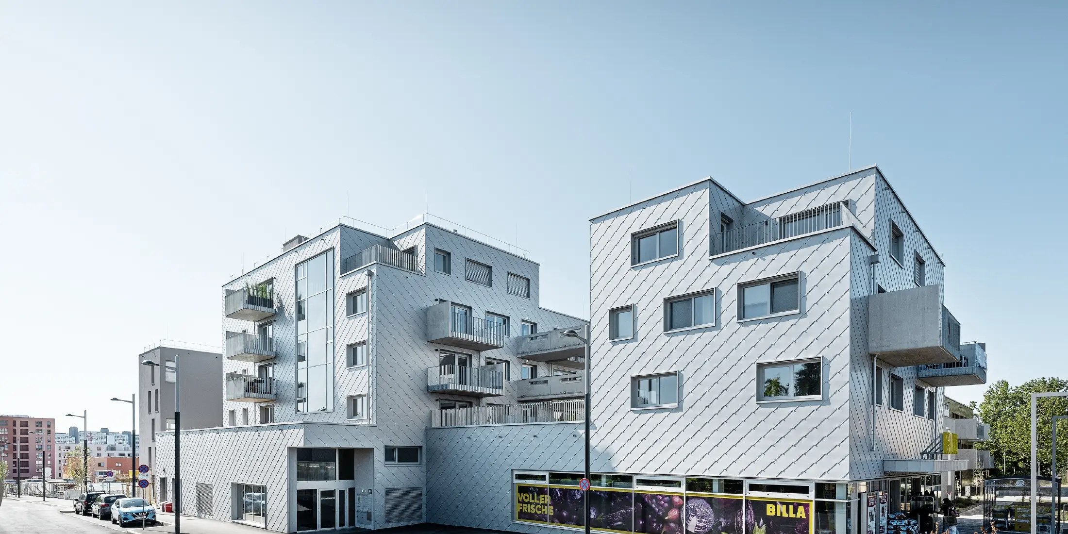 Lakókomplexumok lapos tetővel és rombusz burkolattal a homlokzaton a 44 × 44-es PREFA homlokzatburkoló rombusszal ezüstmetál színben