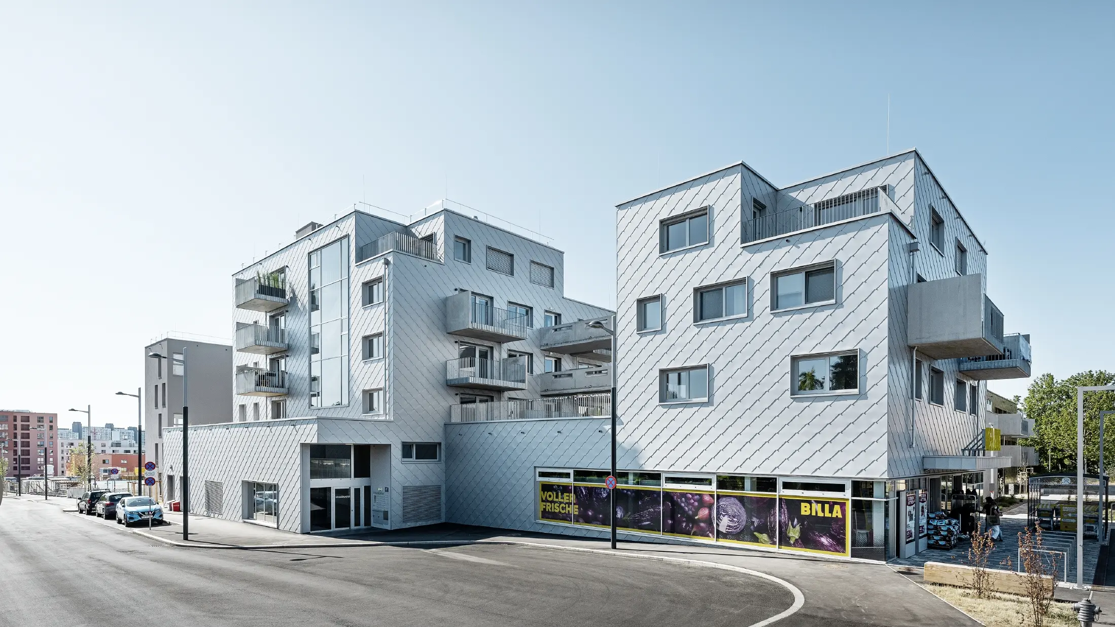 Lakókomplexumok lapos tetővel és rombusz burkolattal a homlokzaton a 44 × 44-es PREFA homlokzatburkoló rombusszal ezüstmetál színben