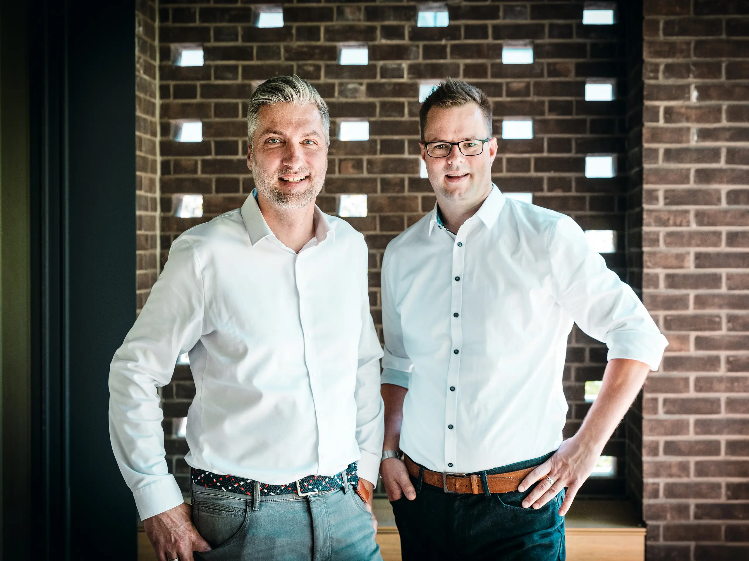 [Translate to Magyar:] Das Architektenteam von A Fiúk Építész Stúdió steht im modernen Innenbereich der Budapester Mehrgenerationen-Villa, die im Rahmen der PREFARENZEN 2026 ausgezeichnet wurde. Vor einer charakteristischen Backsteinwand präsentieren sie die präzise Material- und Formensprache ihres Projekts, das durch das kubische PREFALZ-Aluminiumdach in der Farbe P.10 Anthrazit geprägt ist. Die Szene unterstreicht die architektonische Expertise, die hochwertige Verarbeitung und die bewusste Materialwahl, bei der PREFA Aluminium durch Langlebigkeit, Designstärke und technische Präzision überzeugt.