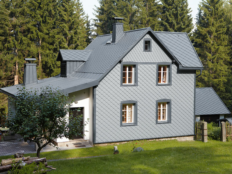 Erdei fekvésű családi ház időjárásálló PREFA alumínium homlokzattal világosszürke színben.