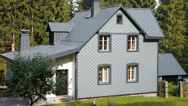 Erdei fekvésű családi ház időjárásálló PREFA alumínium homlokzattal világosszürke színben.