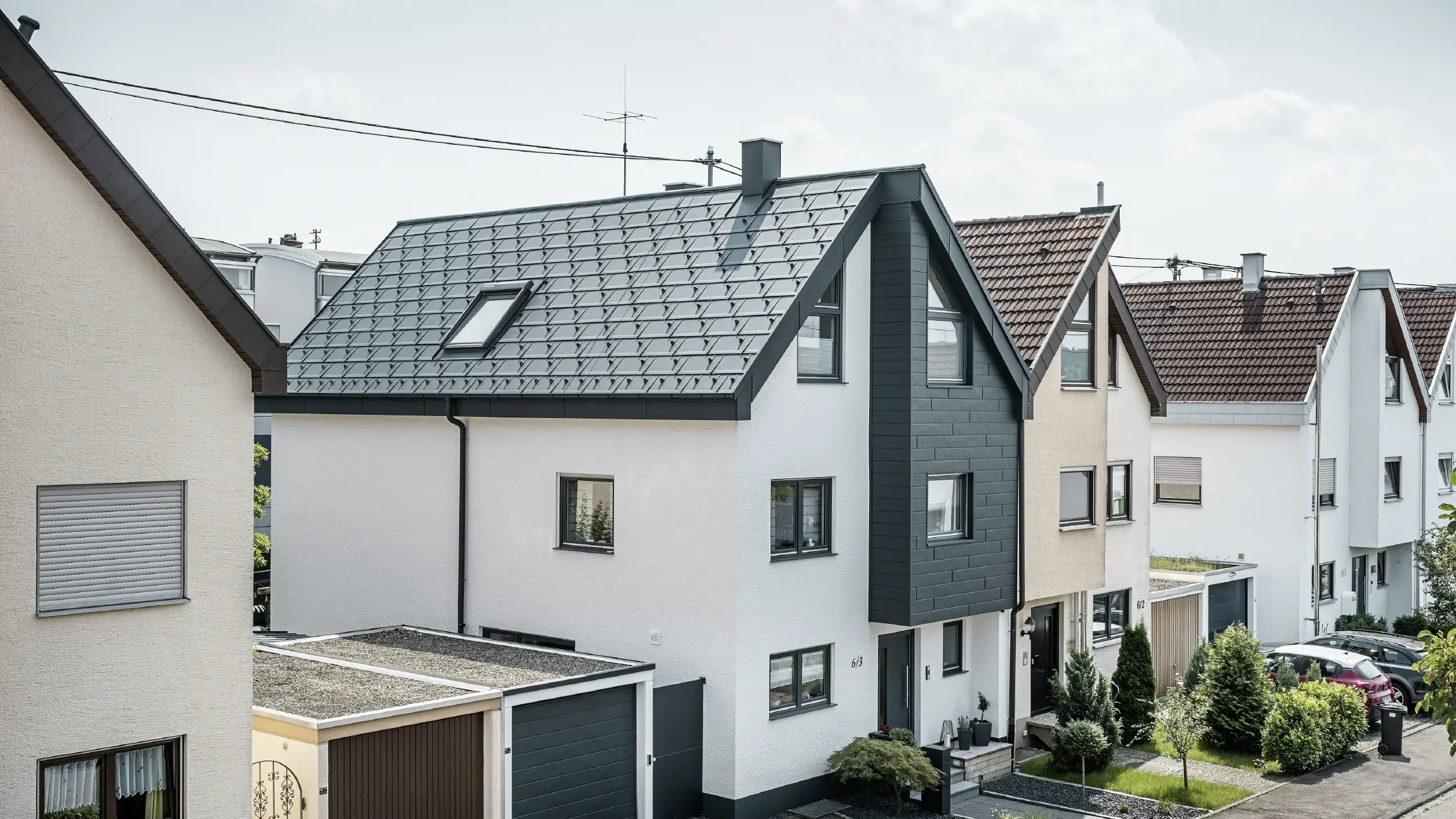 Egy ikerház már fel lett újítva, friss fehér vakolatú homlokzattal PREFA Siding.X homlokzattal, antracit színben. A tetőt PREFA R.16 Classic elem borítja. A tetővizet a szögletes négyszögszelvényű ereszcsatornán vezetik el, beleértve a PREFA lefolyócsövet.