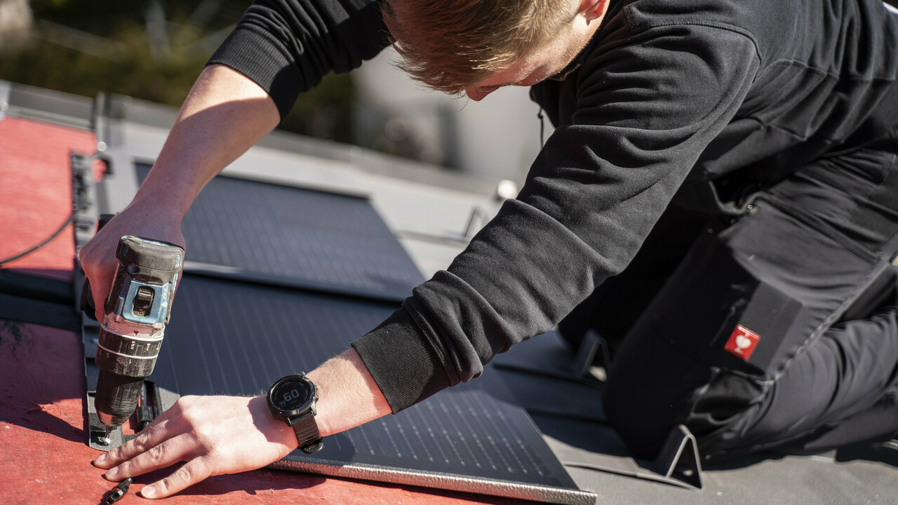 A PREFA egy munkatársa a napelemes tetőfedő panelek beépítése közben.