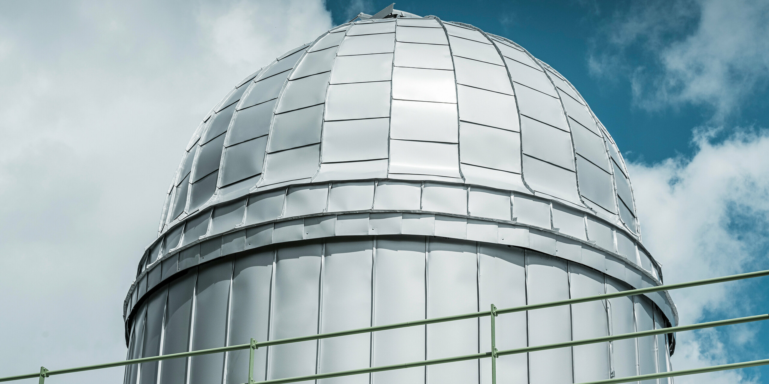 Eine Detailaufnahme der strahlenden Kuppel des Observatoriums von Skalnate Pleso, die mit PREFALZ in Silbermetallic verkleidet ist. Die glänzende Aluminiumverkleidung spiegelt den blauen Himmel wider und symbolisiert die Widerstandsfähigkeit gegen die rauen klimatischen Bedingungen in einer Höhe von 1.783 Metern.