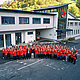 PREFA MitarbeiterInnen mit rotem PREFA T-Shirt stehen in einem Halbkreis vor dem Bürogebäude in Marktl.